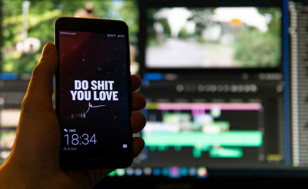 Close-up of a smartphone displaying an inspirational message against a video editing background.